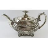A late George III ornate silver teapot with acanthus and scallop decoration standing on a four
