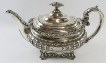 A late George III ornate silver teapot with acanthus and scallop decoration standing on a four