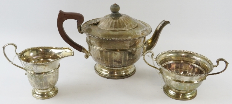 A 1930s J W Benson three piece silver tea set of fluted design, the teapot having fruit wood