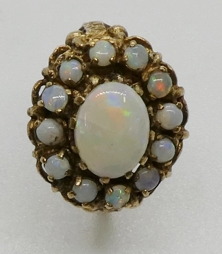 An opal cluster ring, testing as 9ct gold, the central oval opal cabochon measuring 9 x 7mm. 3.9gms. - Image 2 of 3