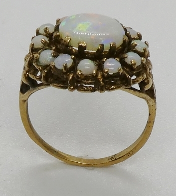 An opal cluster ring, testing as 9ct gold, the central oval opal cabochon measuring 9 x 7mm. 3.9gms. - Image 3 of 3