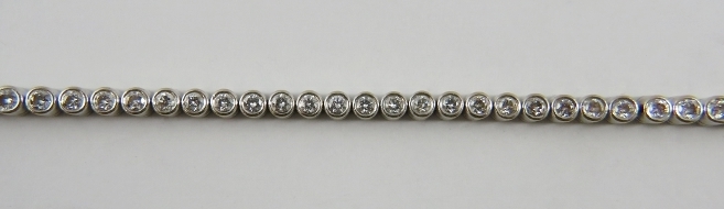 An 18ct white gold diamond line or tennis bracelet, the 60 round brilliant cut diamonds bezel set in - Image 2 of 2