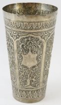 A Far Eastern hand decorated white metal beaker with floral and bamboo panels. Height 14.5cm.