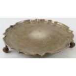 A small silver salver card tray with piecrust edge and standing on three foliate feet. Hallmarked