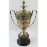 A lidded silver sports trophy with double acanthus leaf handles, pineapple finial and gadrooned