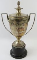 A lidded silver sports trophy with double acanthus leaf handles, pineapple finial and gadrooned
