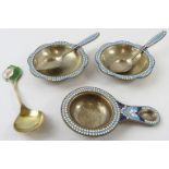 A pair of Russian silver gilt and enamel salts and spoons, a similar tea strainer and a silver