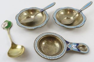 A pair of Russian silver gilt and enamel salts and spoons, a similar tea strainer and a silver