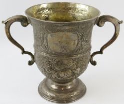 A George II silver loving cup with chased decoration depicting a castle, church and other buildings.