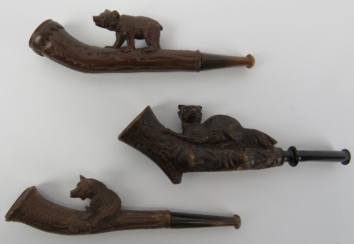 Three Black Forest carved cheroot pipes. Two surmounted with bears and the other with a recumbent