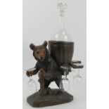 A Black Forest carved wood bear drinks decanter set. Modelled depicting a hiking bear carrying a