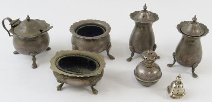Seven mixed silver cruets including salts, mustards and pepperettes. Mostly with blue glass