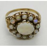 An opal cluster ring, testing as 9ct gold, the central oval opal cabochon measuring 9 x 7mm. 3.9gms.