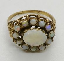 An opal cluster ring, testing as 9ct gold, the central oval opal cabochon measuring 9 x 7mm. 3.9gms.