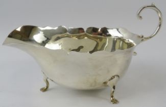 A scallop rimmed silver sauce boat on pad feet, hallmarked for Birmingham 1927, makers Adie Bros.