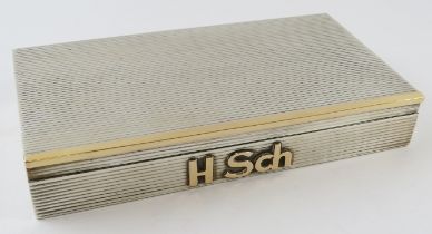 A silver and gold cigarette box with reeded finish and monogram mount. Cedar lined. 18.5cm x 10cm.