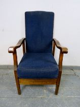 A 1920s oak reclining open-sided armchair, upholstered in navy material with brass studs, the shaped
