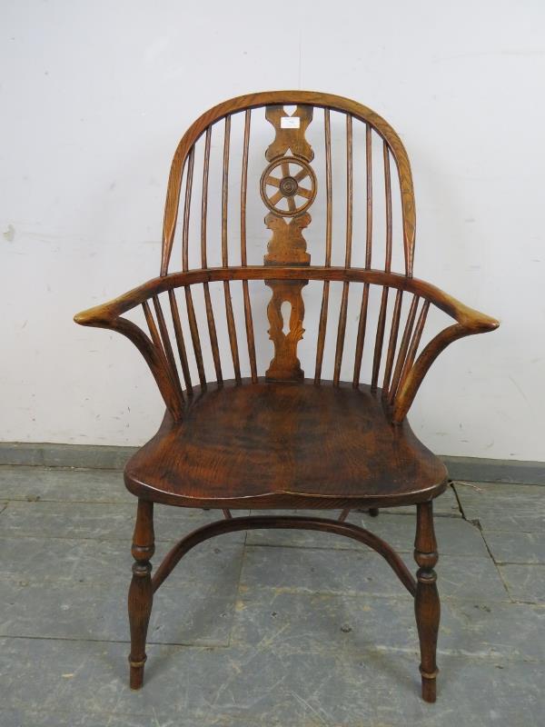 An ash Windsor wheelback chair in the 19th century taste, having carved and pierced back splat,