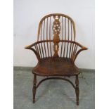 An ash Windsor wheelback chair in the 19th century taste, having carved and pierced back splat,