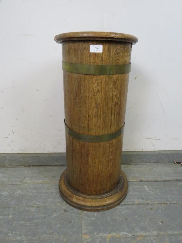 An early 20th century coopered light oak cylinder stick stand, having a tin liner, on a plinth base.