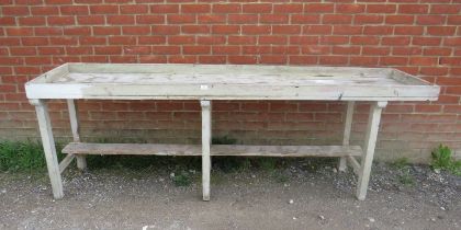 An antique pine potting bench, the galleried planked top on six square supports with stretchers.