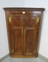 A Georgian oak hanging corner cupboard, the moulded dentil cornice above twin panelled doors with