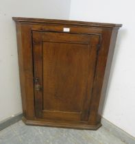 A Georgian oak wall-hanging corner cupboard, the panelled door opening onto two fitted shelves.