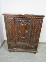 A 17th century Italian oak side cabinet, the chip carved frieze above profuse relief carved decorat