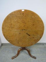 A 19th century medium oak tilt-top supper table, on a ring turned column with splayed tripod