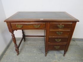 An Edwardian mahogany kneehole desk, housing a configuration of five graduated oak-lined drawer with