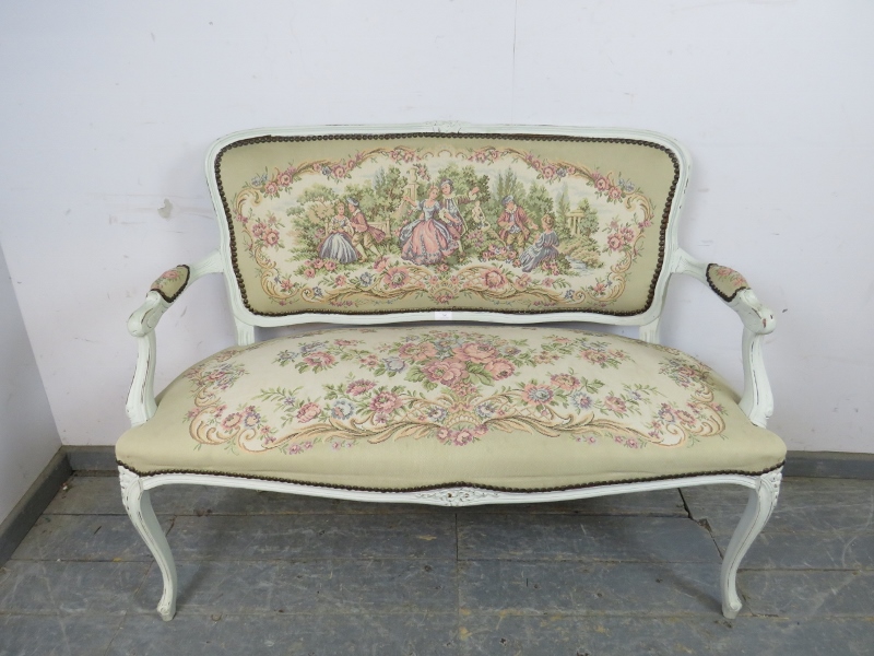 A vintage French two-seater sofa, painted white and distressed, upholstered in tapestry material