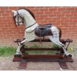 A vintage dapple-grey rocking horse, with real horsehair mane and tail and leather saddle and