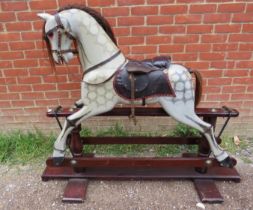 A vintage dapple-grey rocking horse, with real horsehair mane and tail and leather saddle and