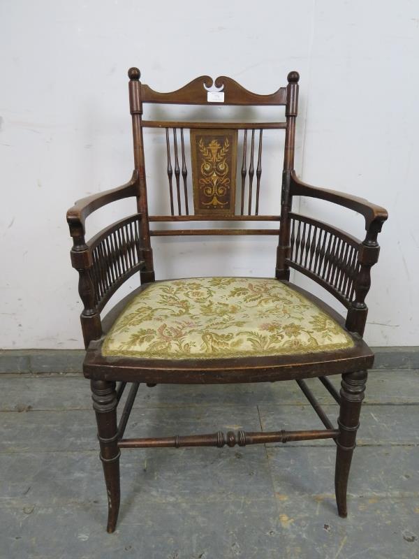 An Edwardian mahogany elbow chair, having marquetry inlaid back panel and turned spindles, above a