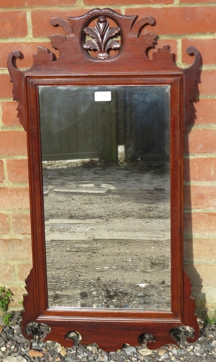 An antique mahogany bevelled wall mirror in the Georgian taste, the carved and pierced surround with