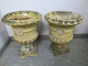 A pair of weathered terracotta garden urn planters, having egg and dart moulding and fluted