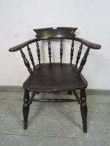 A turn of the century ebonised captain’s chair, carved with the initial ‘M’ the scrolled arms joined