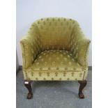 An antique mahogany tub chair in the Georgian taste, upholstered in patterned material with brass