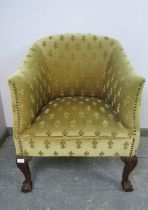 An antique mahogany tub chair in the Georgian taste, upholstered in patterned material with brass