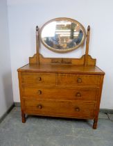 An Art Deco Period medium oak dressing chest, the bevelled oval swing mirror above a base housing