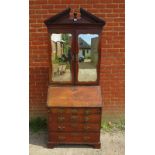 An 18th century mahogany bureau bookcase, the broken pediment with turned centre finial and dentil