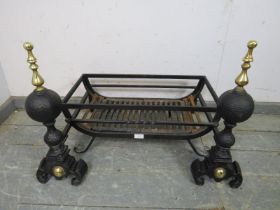 A pair of antique style cast iron and brass fire dogs, together with a wrought iron fire basket,