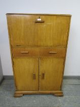 A vintage Art Deco Revival light oak drinks cabinet, the top section with fall front and rising