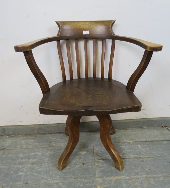 An Edwardian elm captain’s swivel desk chair, on four shaped supports. H79cm W65cm D48cm (approx).