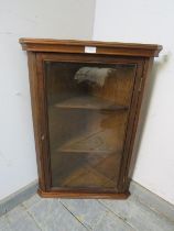 A reproduction mahogany wall hanging glazed corner cupboard, having a moulded cornice above two