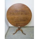 A Georgian oak tilt-top circular supper table, on a tapered turned column with splayed tripod