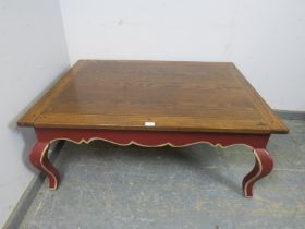 A reproduction oak rectangular coffee table, the burgundy painted base with shaped frieze above ogee