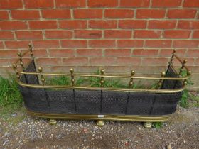 An Edwardian brass and wire mesh fire fender, the ball finials above turned brass spindles, with