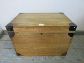 A small vintage pine flat topped trunk, having metal bound corners and recessed handles to either