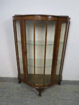 An Art Deco Period demi-lune glazed display cabinet, having two loose glass shelves, on ogee